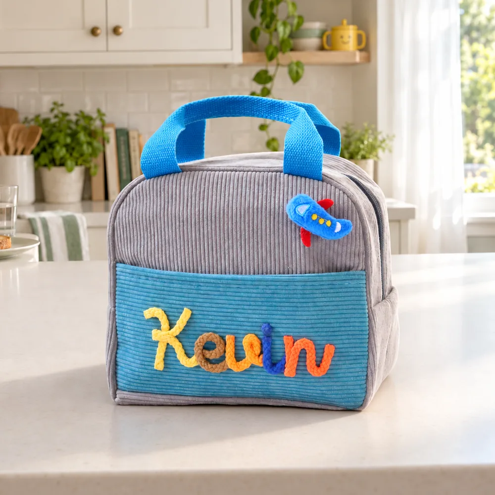 Personalized insulated corduroy lunch bag in gray and blue with raised yarn name lettering.
